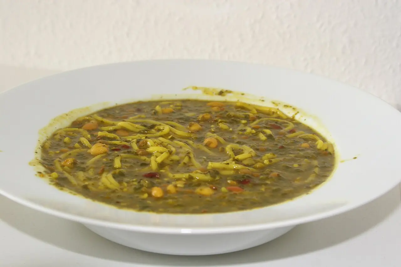 بشقاب گودی از آش رشته با رشته، حبوبات و سبزی