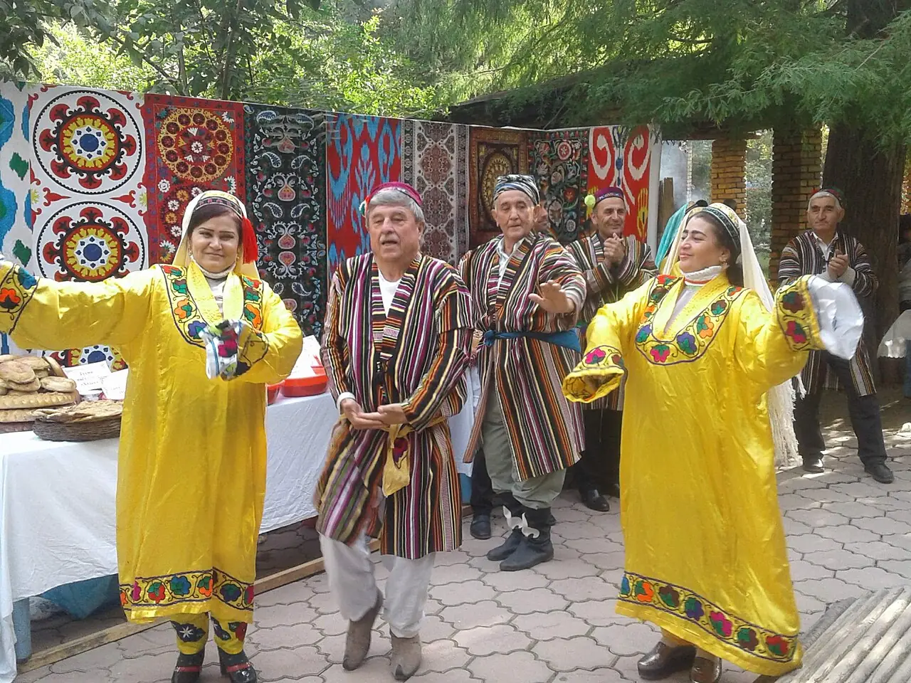 زنان با پیراهن زرد و مردان با چپن راه‌راه در جشن مهرگان در پارکی در دوشنبه می‌رقصند