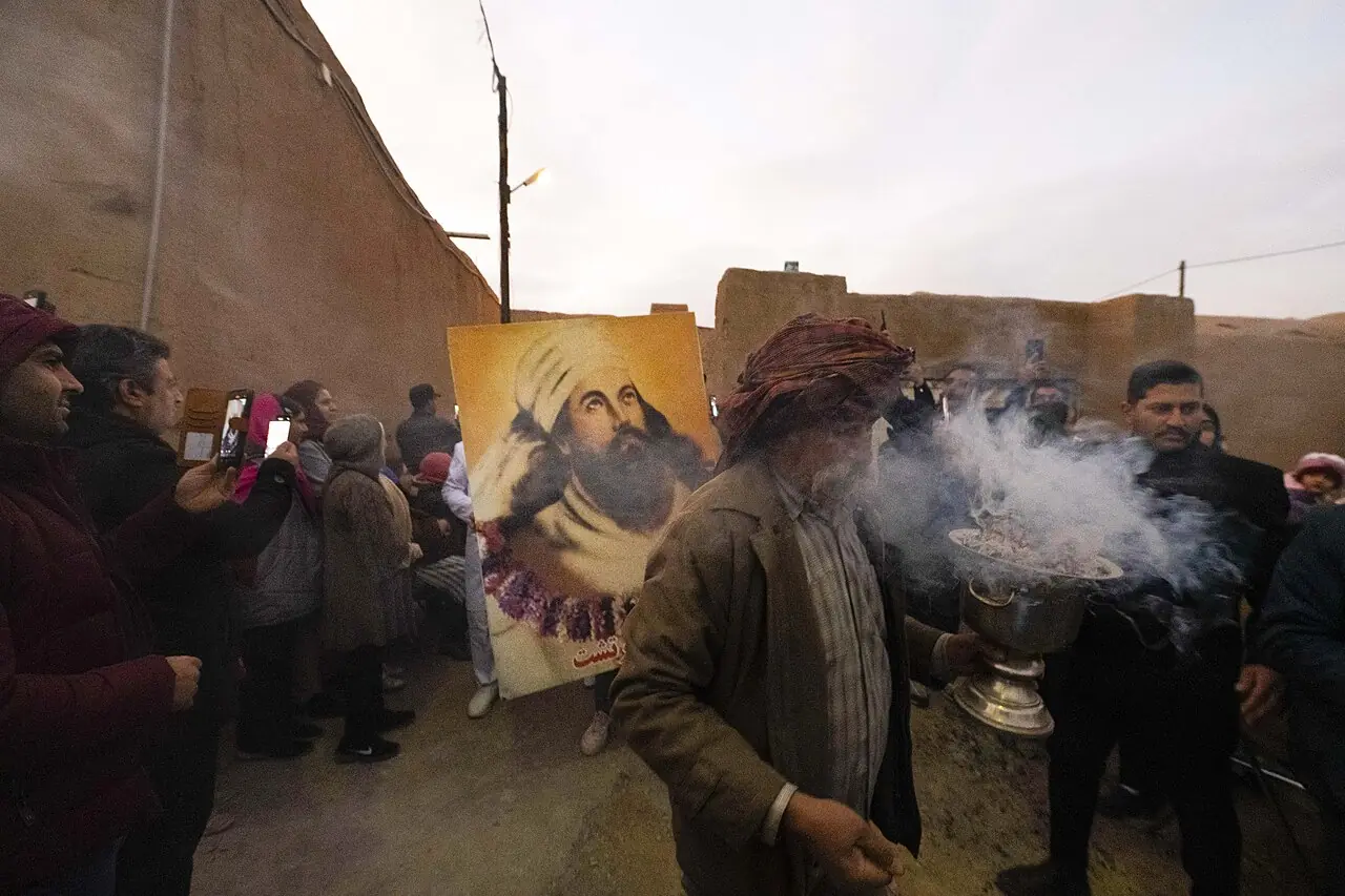 مردی با دستار، آتشدانی دودکنان را میان جمعیت می‌گرداند و پشت سرش تصویری از زرتشت دیده می‌شود