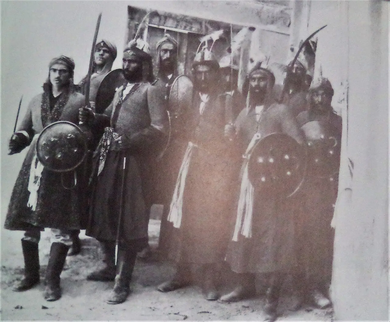 عکس سیاه‌وسفید قدیمی از گروهی از بازیگران تعزیه با کلاه‌خود، سپر و شمشیر